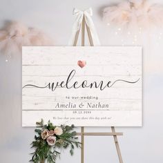 a welcome sign is hanging on a easel with flowers and feathers in the background