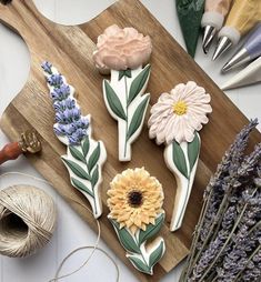 some flowers are sitting on a cutting board next to yarn and scissors, spools of twine