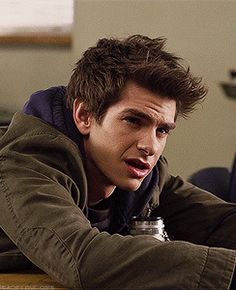 a young man sitting at a table with his hand on his chin and looking to the side