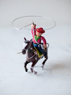 a figurine of a man riding a horse with a lasso on its back