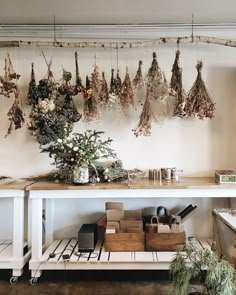 a bunch of dried flowers are hanging on the wall above a table in a shop