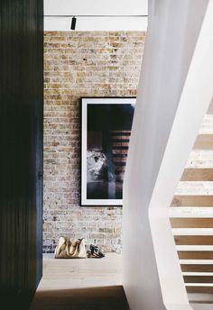 a pair of shoes sitting on top of a wooden floor next to a brick wall