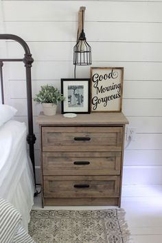 a bed room with a neatly made bed and a wooden dresser next to a lamp