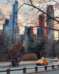 yellow taxi cabs driving down the road in front of tall buildings with skyscrapers