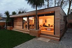 a small wooden house sitting on top of a lush green field next to a palm tree