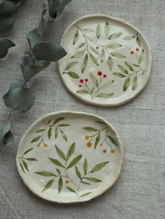 two plates with leaves and berries painted on them