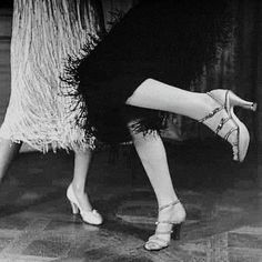 a woman is dancing on the floor with her foot in the air and wearing high heels