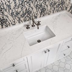 a white sink sitting under a bathroom mirror next to a wall mounted faucet