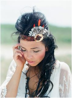 a woman with long hair wearing a flower headband and holding her hand to her ear