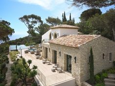 an aerial view of a house with stone walls and roofing, surrounded by trees