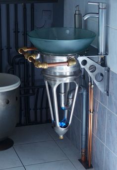 a bathroom sink sitting next to a bath tub in a room filled with pipes and fixtures