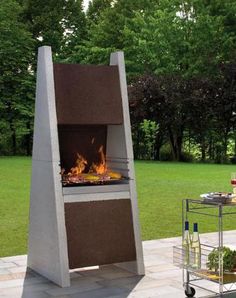 an outdoor fire pit sitting in the middle of a field with bottles and glasses on it