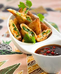 a white bowl filled with food next to a dipping sauce on top of a table