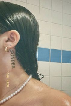 a woman with tattoos on her neck and behind her ear is looking in the mirror