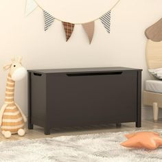 a toy chest sitting on top of a rug next to a stuffed giraffe