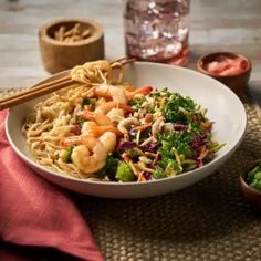 a white bowl filled with shrimp and broccoli on top of a wooden table