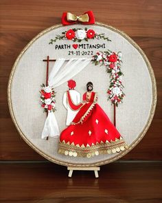 a cross stitched picture of a man and woman in red wedding dress on a wooden table