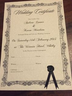 a wedding certificate with a black ribbon on the front and back of it, sitting on top of a wooden table