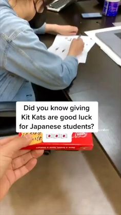 a woman sitting at a desk with a piece of paper in front of her and the caption did you know giving kitkats are good luck for japanese students?