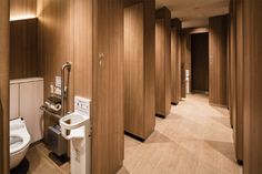 a bathroom with wooden walls and flooring next to a white toilet in a restroom