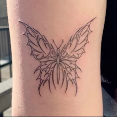 a small butterfly tattoo on the side of a woman's leg, it is black and white