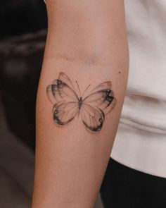 a woman's arm with a black and white butterfly tattoo on the left forearm