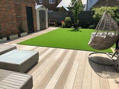 a backyard with wooden decking and artificial grass on the ground, including a hammock chair