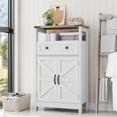 a white cabinet sitting next to a window in a room filled with towels and other items