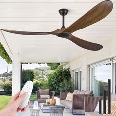 a person holding a remote control in front of a ceiling fan on a covered porch