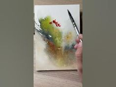 a person is holding a paintbrush and drawing on paper with watercolor pencils