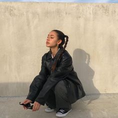 a woman sitting on the ground in front of a wall