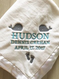 a personalized towel with two baby feet on it and the name hudson dennis cream