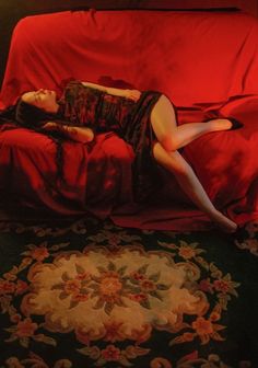 a woman laying on top of a red couch