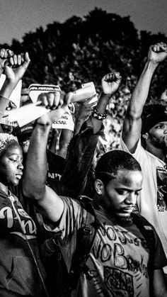 black and white photograph of people holding up their hands in the air at a sporting event