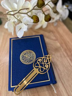 a blue book sitting on top of a wooden table next to white and green flowers