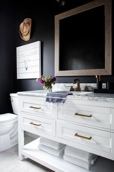 a white bathroom with black walls and gold trim on the vanity, toilet and mirror