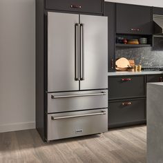 a stainless steel refrigerator in a kitchen with black cabinets and wood flooring on the walls