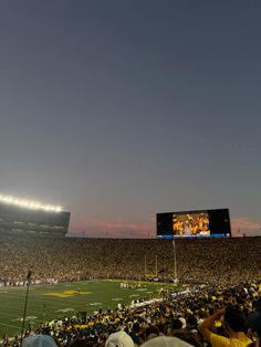 a football stadium filled with lots of people watching a game on the big screen tv