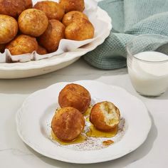 some food is sitting on a white plate next to a glass of milk and bowl of potatoes