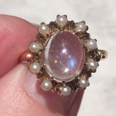 Stunning Vintage cabochon moonstone surrounded by luminous pearls.The dreamy of moonstone goes through from silvery clear to a blue hued moonstone, a lovely combination.The moonstone has several natural round inclusions and one tiny nick, near the end of the oval moonstone, only noticeable with a jewellers magnifying loupe. The pearls are lustrous and firmly claw set as is the moonstone.The ring has a simple 10ct gold shank, with a simple gold  ring band decoration.The vintage ring is in a good Vintage Oval Cabochon Moonstone Ring, Antique Gold Moonstone Ring Oval Cabochon, Vintage Cabochon Moonstone Ring, Luxury Vintage Moonstone Oval Cabochon Ring, Antique Moonstone Ring, Oval Cabochon, Pearl Gold Ring, Simple Gold Ring, Gold Ring Band, Gold Rings Simple