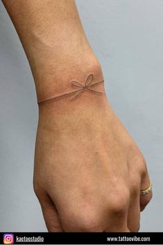 a woman's hand with a small bow on it and a string attached to the wrist