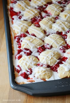 a pan filled with desserts covered in icing and toppings on top of a wooden table