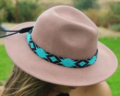 a woman wearing a brown hat with blue beading on the brim and black band