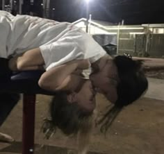 a man and woman kissing while sitting on a bench