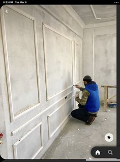 a man in blue jacket painting a white wall