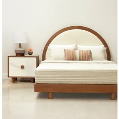 a bed with white sheets and pillows in a room next to a night stand that has two nightstands on both sides