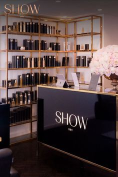 the front desk of show day with flowers in vase and bookshelves behind it