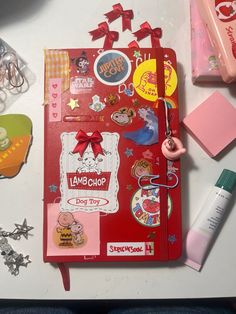 a red notebook covered in lots of stickers and magnets on top of a table