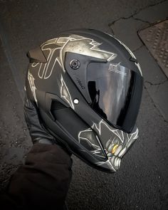 a motorcycle helmet sitting on top of a persons hand next to the road with it's visor up