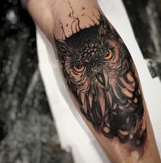 an owl tattoo on the arm with orange eyes and black ink is shown in this image